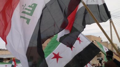 رفع العلمين العراقي والسوري الجديد في تجمع سابق