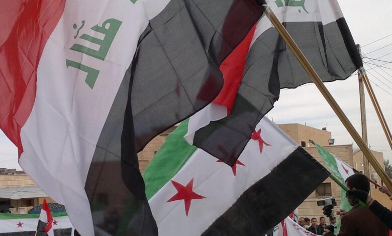 رفع العلمين العراقي والسوري الجديد في تجمع سابق